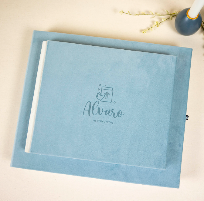 Álbum de comunión de tapa azul con nombre Álvaro sobre mesa