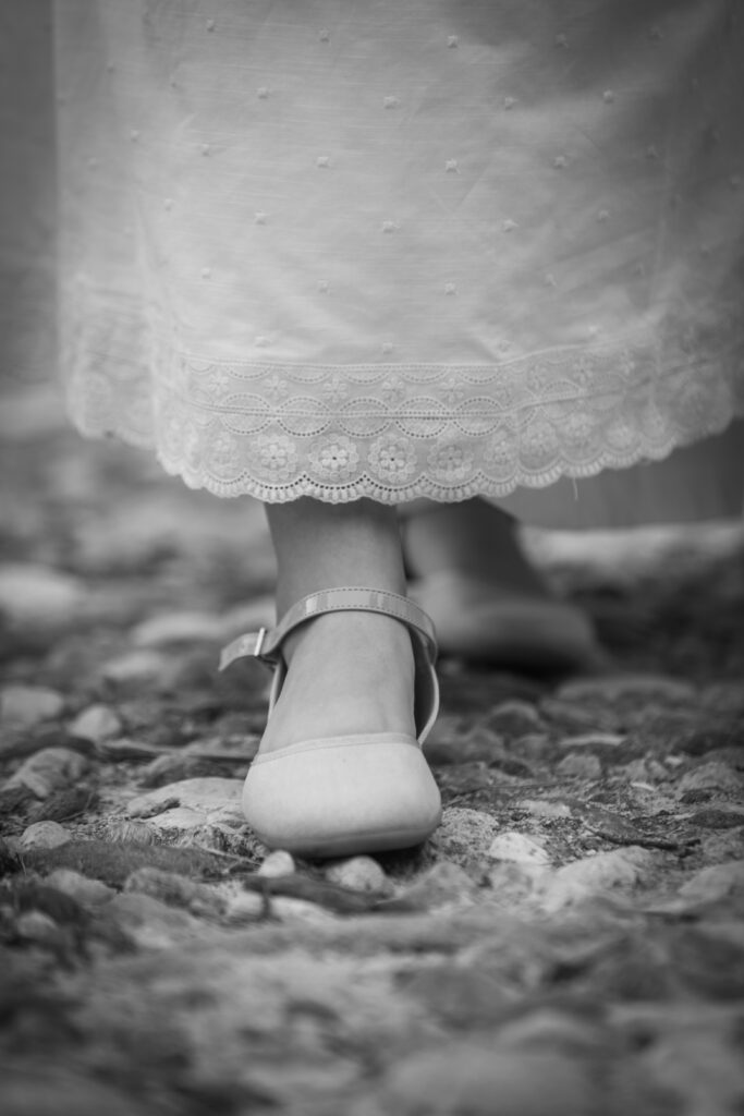 Detalle en blanco y negro de zapato y vestido de comunión de niña