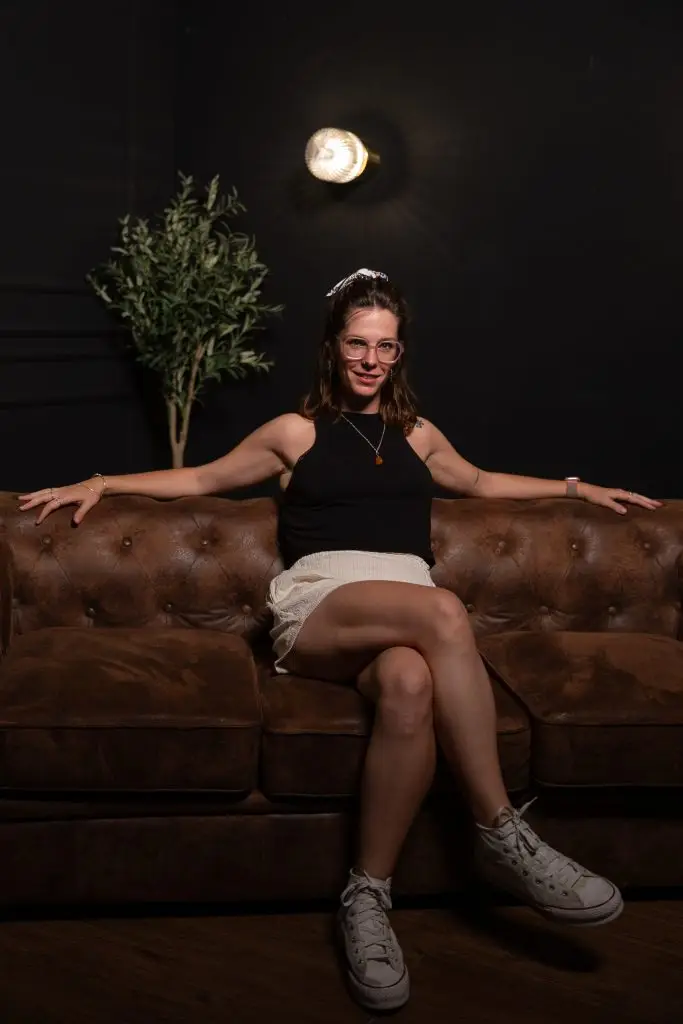 Mujer posando en sofá oscuro