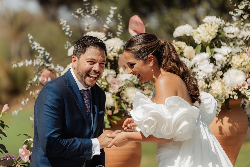 Pareja riendo al poner el anillo.