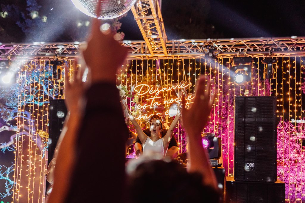 Persona celebrando en la pista de baile bajo luces y bola de discoteca.