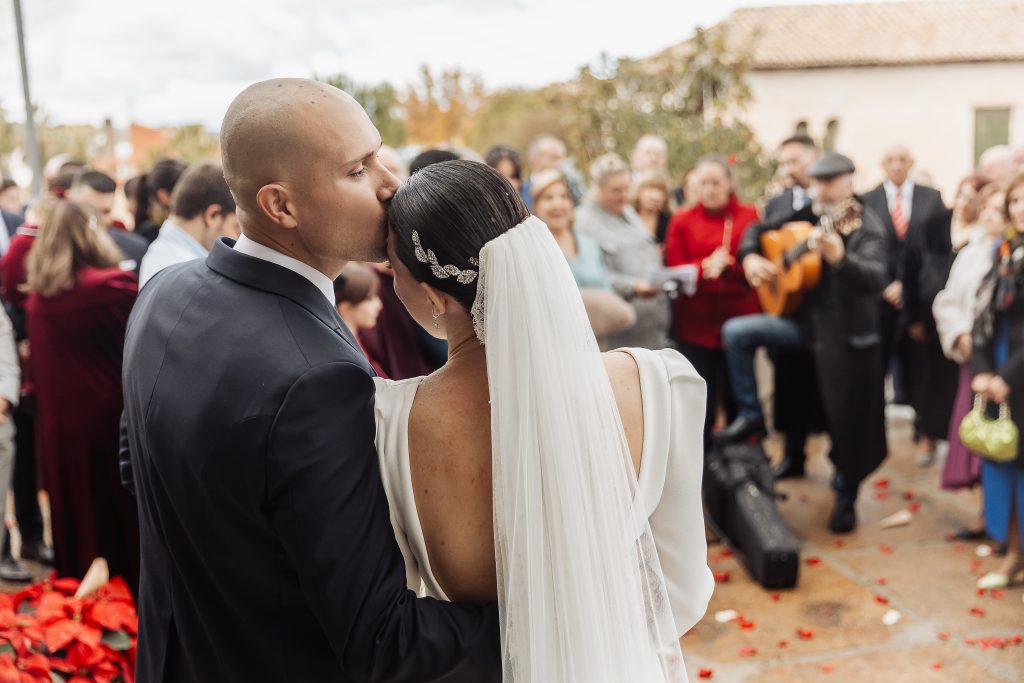 Novio besando la frente de la novia en exterior.